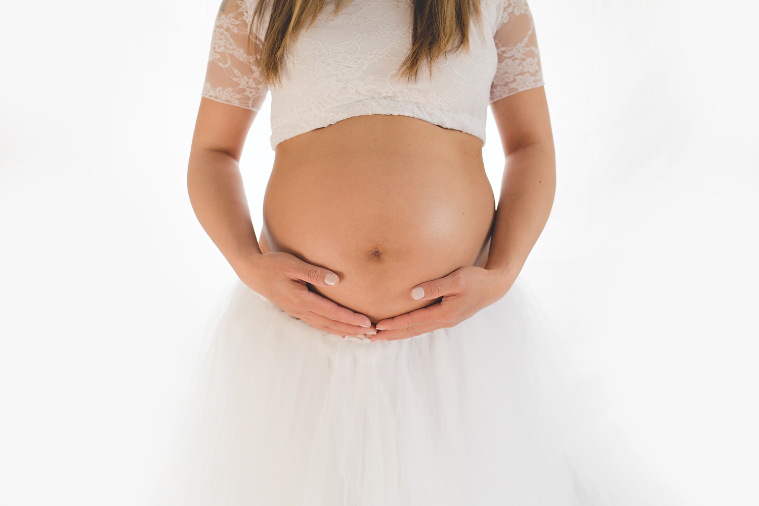 Expectant mom photographed in white tutu for her maternity session.
