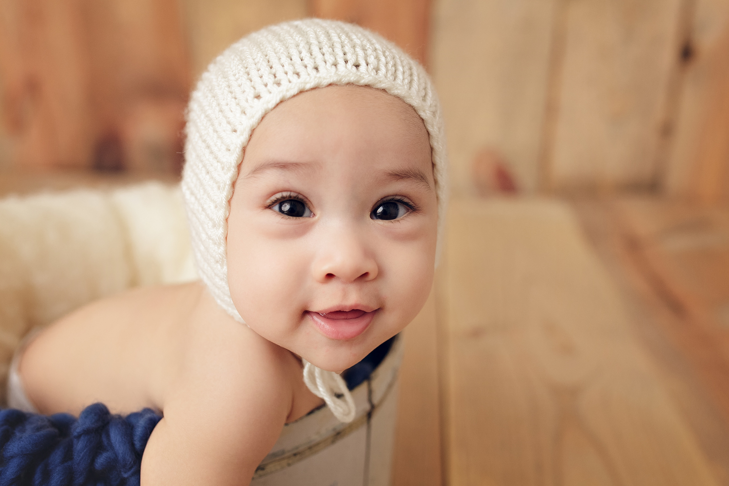 Baby T in a bonnet during his photo shoot is smiling. 