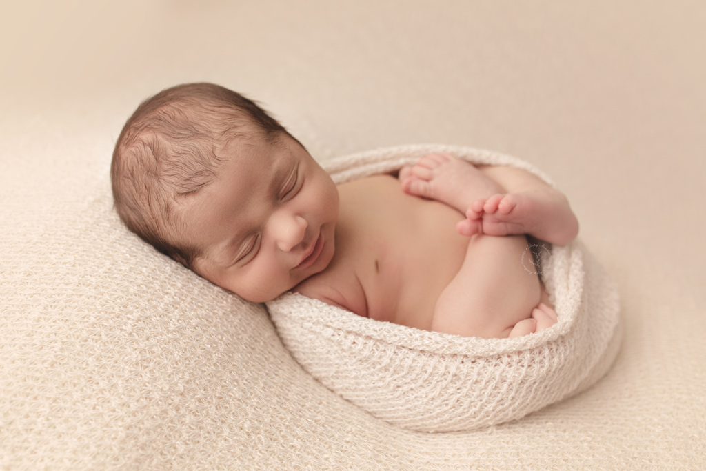 Baby wrapped in cloth fabric posing for newborn pictures during his photo session.