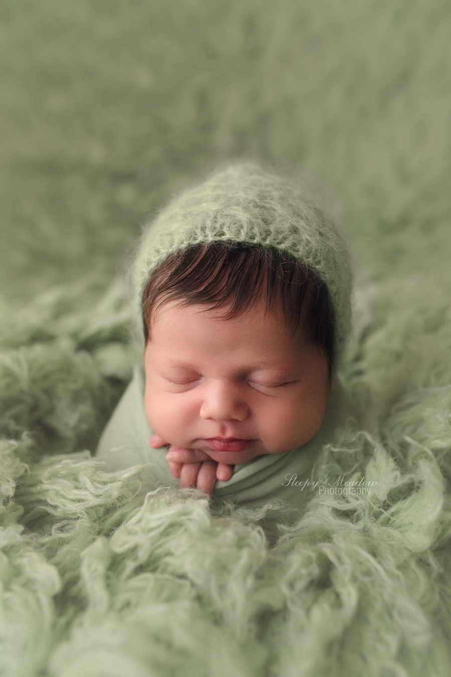 Newborn boy poses on green flokati rug wearing a green bonnet | Sleepy Meadow Photography | Milwaukee Newborn Photographer