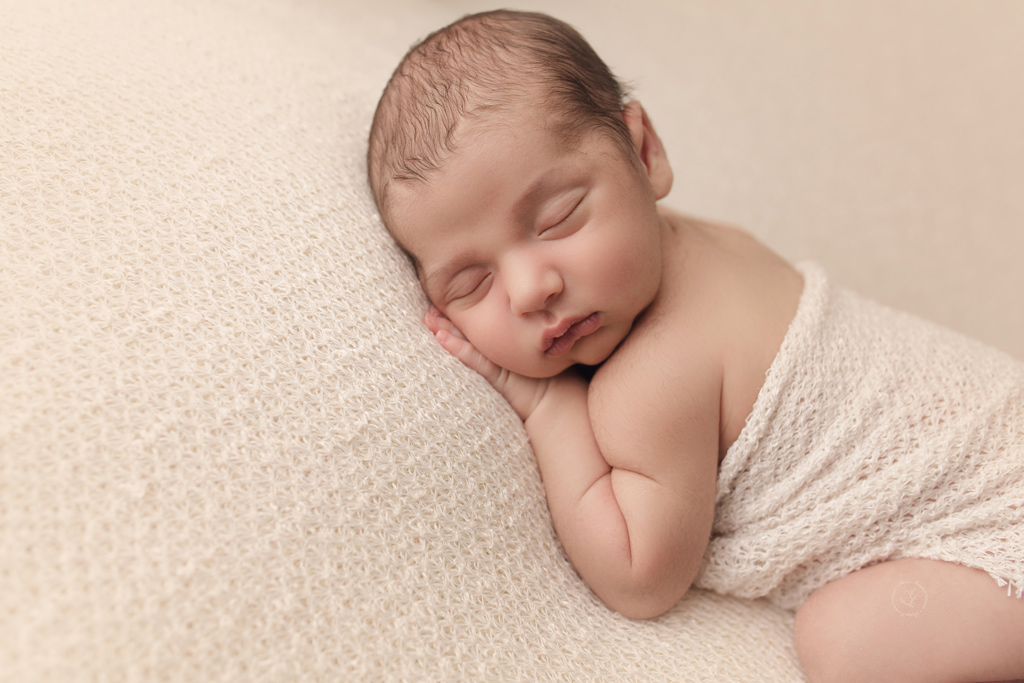 Newborn baby photographed on cream backdrop at Sleepy Meadow Photography for his first photoshoot.