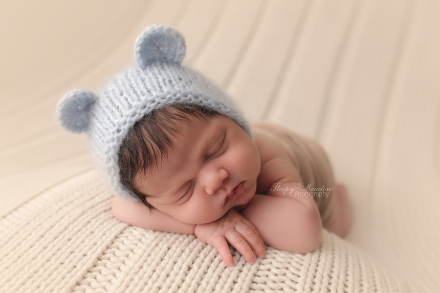 Newborn boy wearing bear bonnet for his photo shoot by Sleepy Meadow Photography.