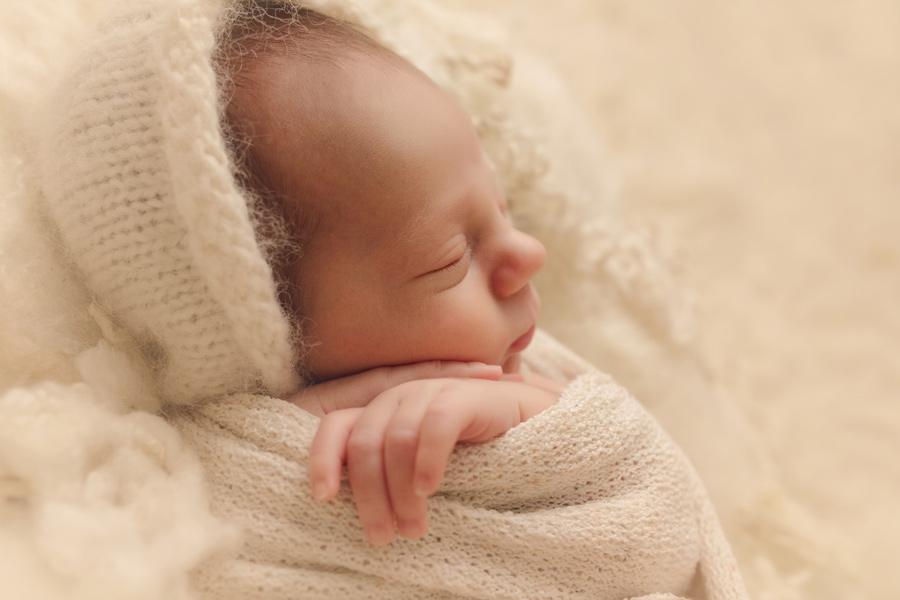 Professional newborn pictures are done in the first few days of life. Newborn baby boy wearing a bonnet for his first photo shoot.