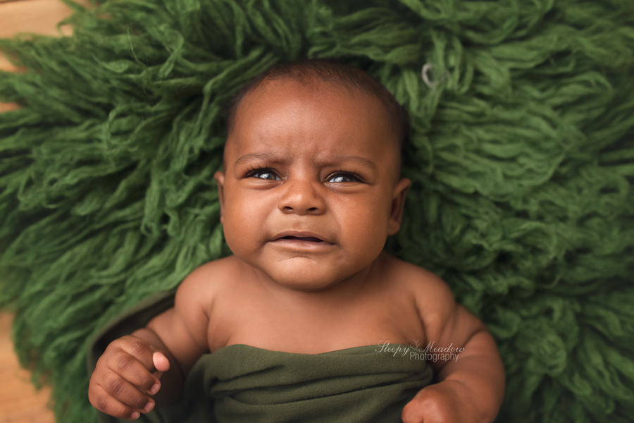 Milwaukee's best baby and newborn photographer takes pictures of baby roosevelt on green flokati rug at her studio located in Brookfield, WI.