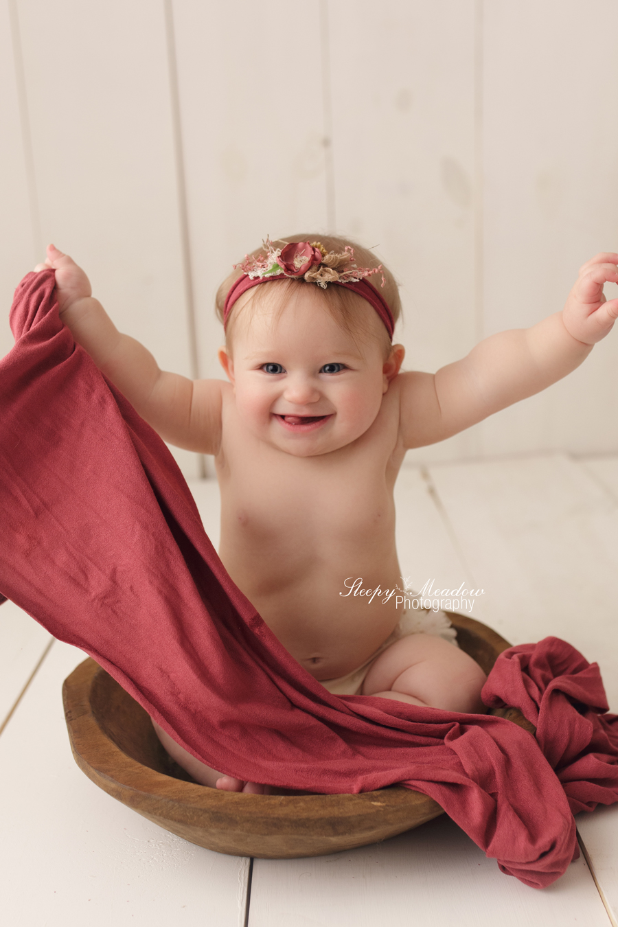 Baby girl poses in wooden bowl for her professional baby pictures in Milwaukee.