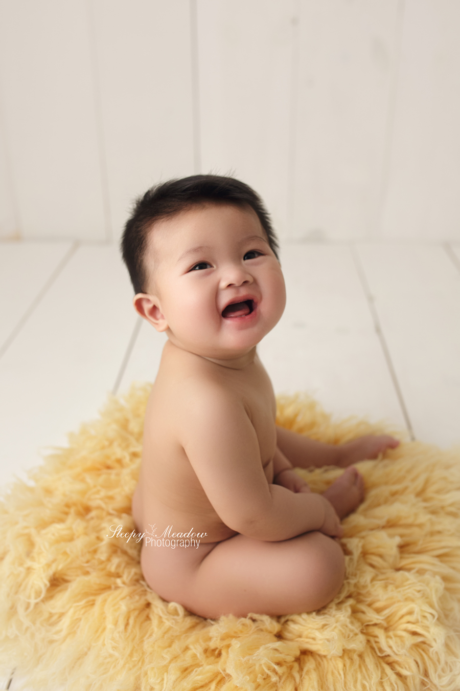 Baby poses on yellow luneberry flokati rug for his milestone session with Sleepy Meadow Photography.