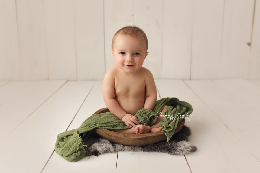8 month old baby boy photographed in a wooden bowl with rabbit fur for a prop during his photo shoot with Sleepy Meadow Photography.