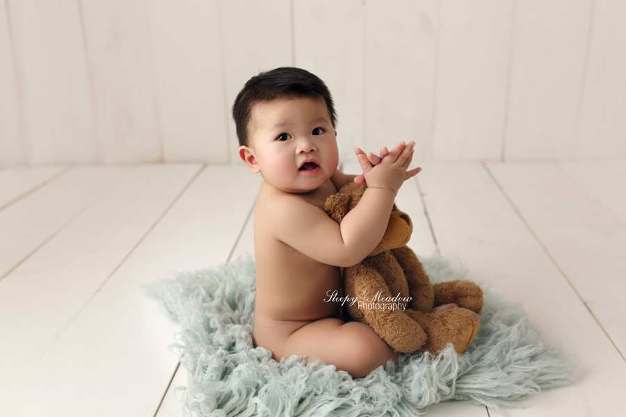 Baby poses with teddy bear on a wood backdrop for his 7 month session.