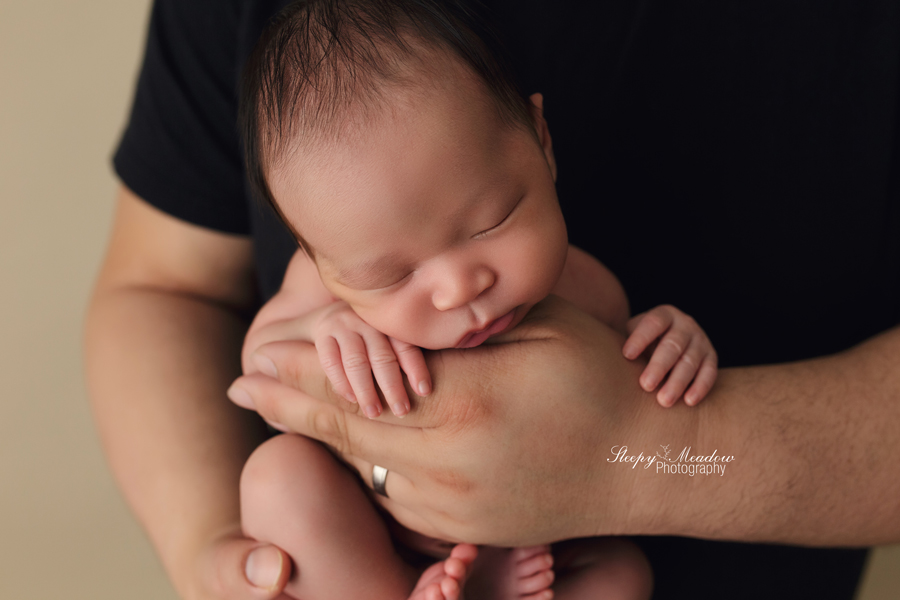 Adorable baby boy posed in his dad's hands for his newborn session in Milwaukee.