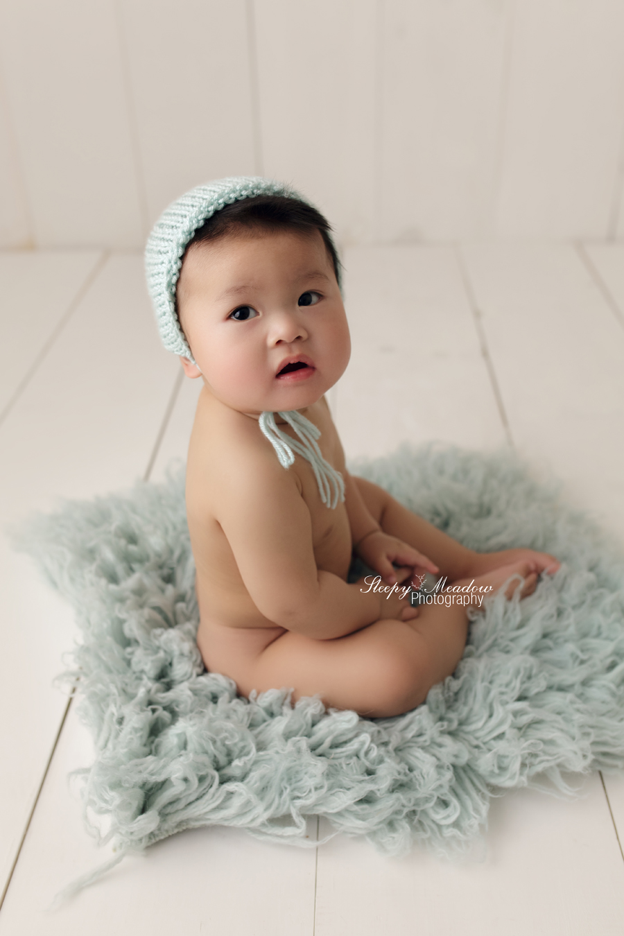 7 month old baby wears a blue bonnet for his photo shoot with Sleepy Meadow Photography.