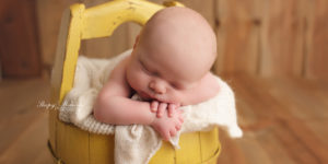 Sweet newborn boy poses in yellow bucket in Milwaukee | Sleepy Meadow Photography