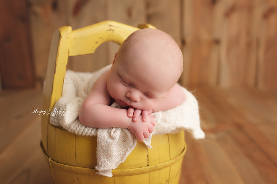 One of Milwaukee's best newborn photographers takes picture of baby in yellow basket | Sleepy Meadow Photography