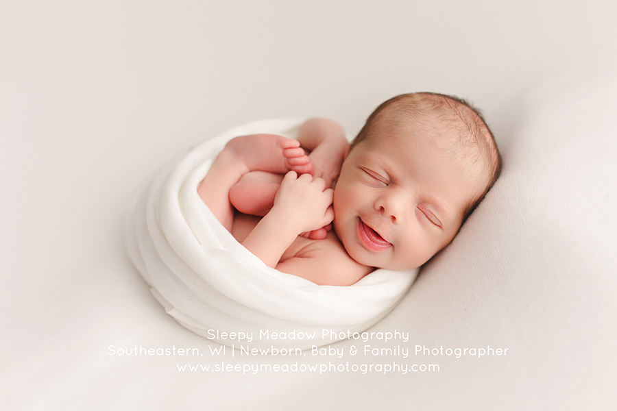 Amelia smiling for her newborn session with Sleepy Meadow Photography