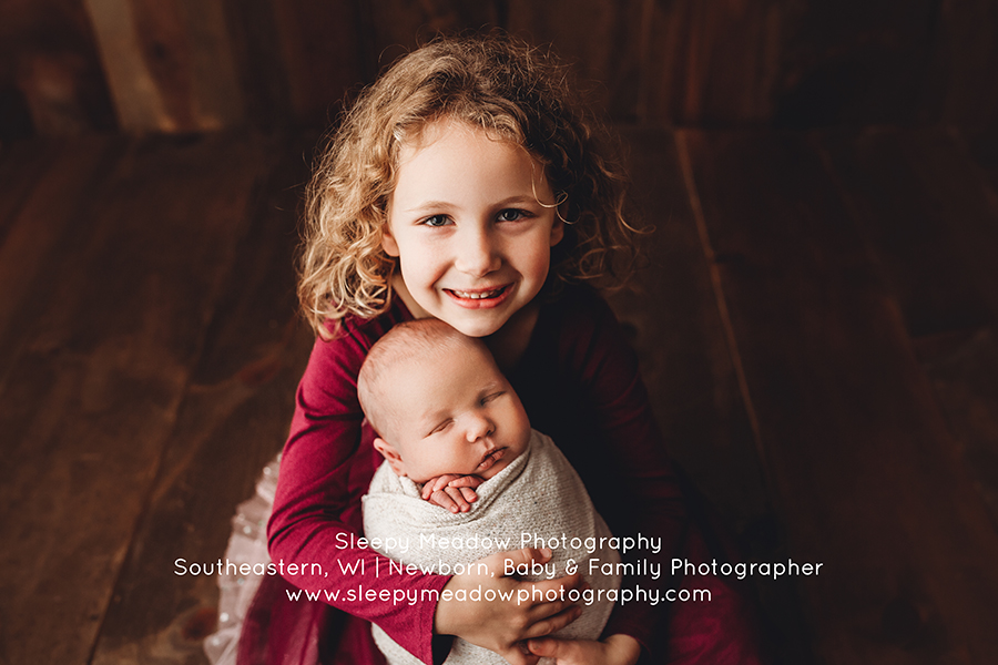Sister holds new baby brother || Newborn Photographer Ozaukee