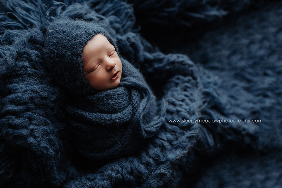 baby boy wearing blue bonnet and wrapped in knit blue scarf