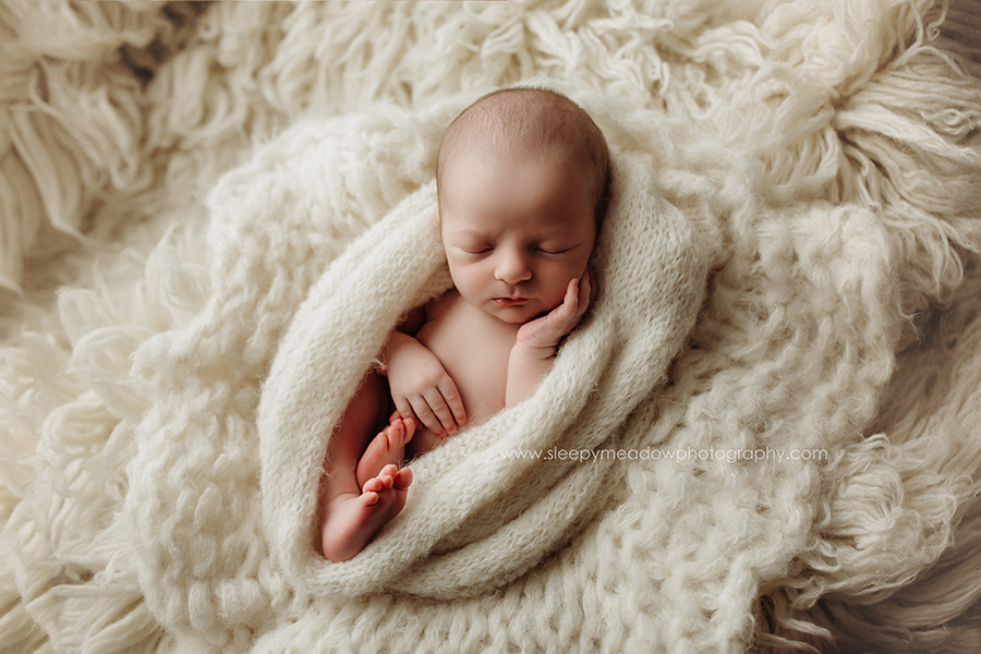 newborn boy posing holding his cheek